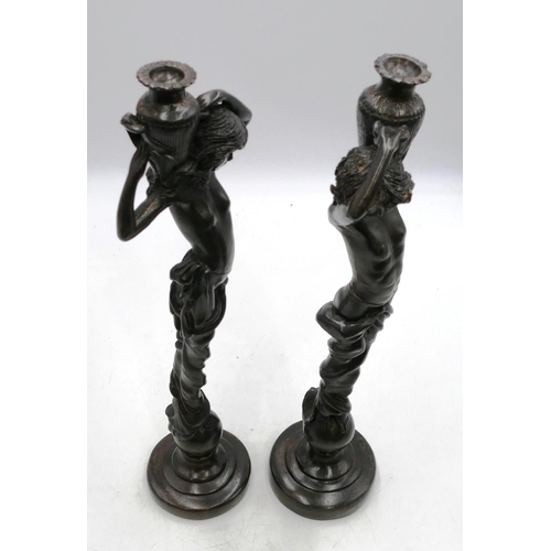 764 - A pair of bronze candlesticks in form of half-naked ladies holding urns above their heads, on round ... 