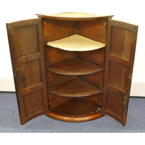 861 - A George III mahogany hanging bow fronted corner cupboard with 2 panel doors, enclosing shelves, 65.... 