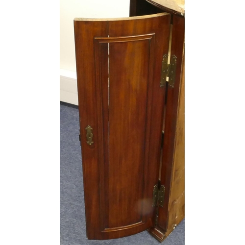 861 - A George III mahogany hanging bow fronted corner cupboard with 2 panel doors, enclosing shelves, 65.... 