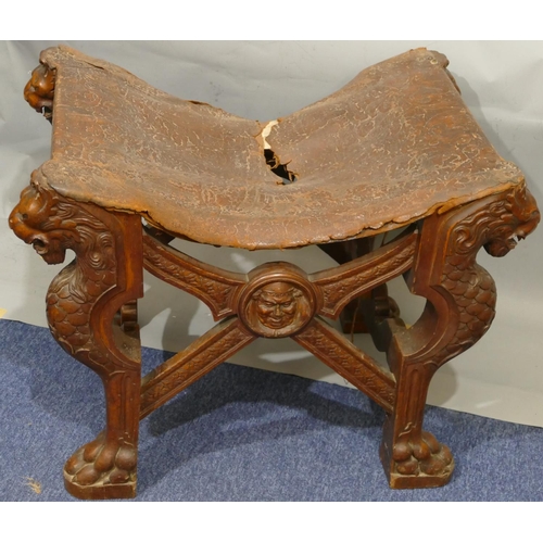 869 - A 19th Century large heavily carved oak stool with concave leather seat (leather in need of restorat... 