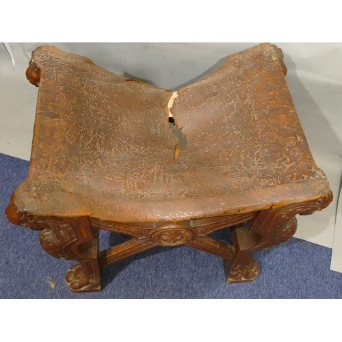 869 - A 19th Century large heavily carved oak stool with concave leather seat (leather in need of restorat... 