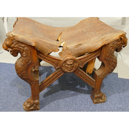 869 - A 19th Century large heavily carved oak stool with concave leather seat (leather in need of restorat... 