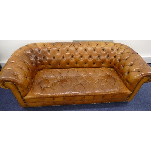 872 - A brown leather Chesterfield settee with buttoned seat, back and arms, part studded decoration, on c... 