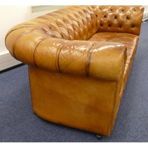 872 - A brown leather Chesterfield settee with buttoned seat, back and arms, part studded decoration, on c... 