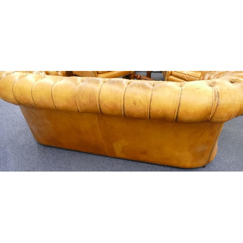 872 - A brown leather Chesterfield settee with buttoned seat, back and arms, part studded decoration, on c... 