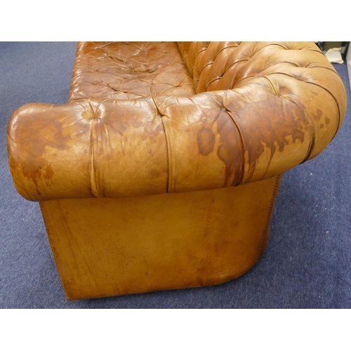 872 - A brown leather Chesterfield settee with buttoned seat, back and arms, part studded decoration, on c... 