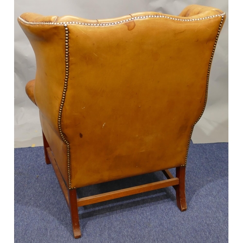 874 - A mahogany framed and brown leather wing back armchair with buttoned back, arms and wings, part stud... 