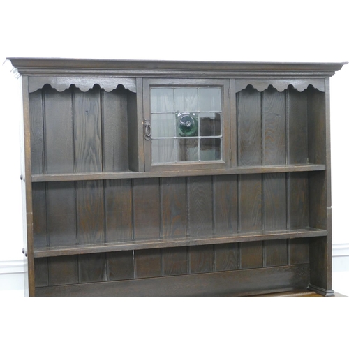 878 - A 1920's oak dresser with small leaded glass panelled door surrounded by shelves, 1 long drawer and ... 