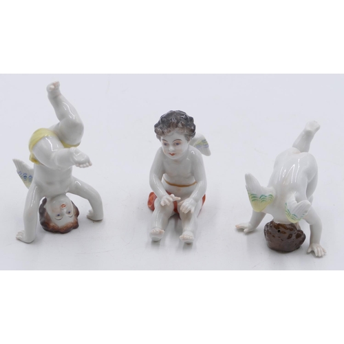 101 - A set of 3 Continental porcelain figures of cupids seated and doing handstands, largest 10.5cm high.... 