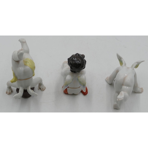 101 - A set of 3 Continental porcelain figures of cupids seated and doing handstands, largest 10.5cm high.... 