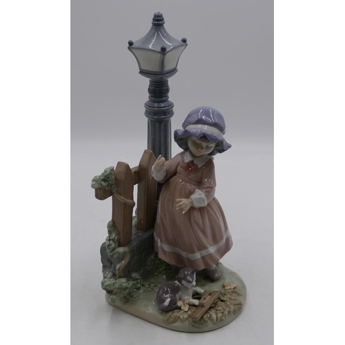 114 - A Lladro figure of a young girl and kitten standing next to street lamp and fence, 33cm high.