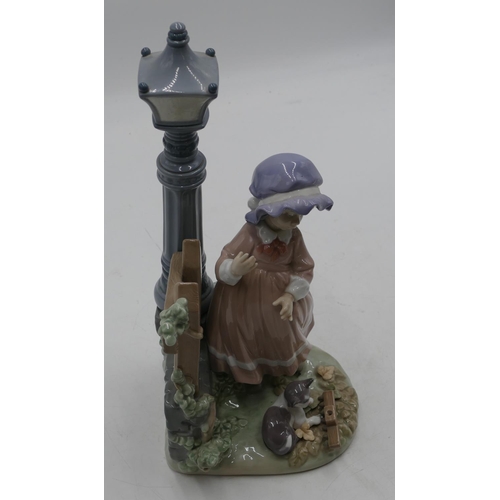 114 - A Lladro figure of a young girl and kitten standing next to street lamp and fence, 33cm high.