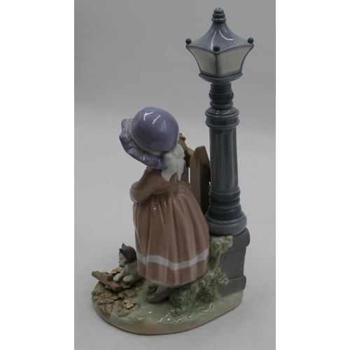 114 - A Lladro figure of a young girl and kitten standing next to street lamp and fence, 33cm high.