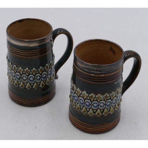 17 - A pair of 19th Century Royal Doulton glazed earthenware tankards with silver rims on green and brown... 