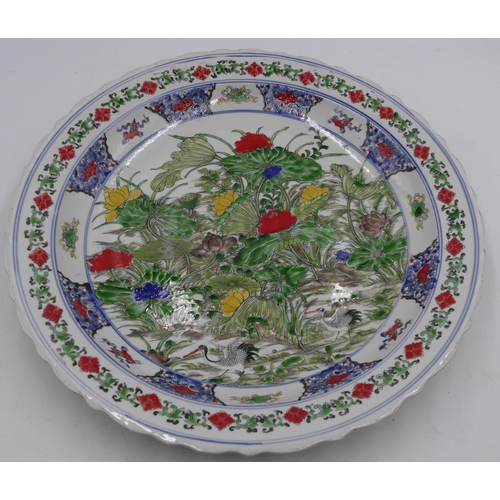 23 - A 20th Century Chinese round charger with crinkled rim on white ground with multi-coloured floral, l... 