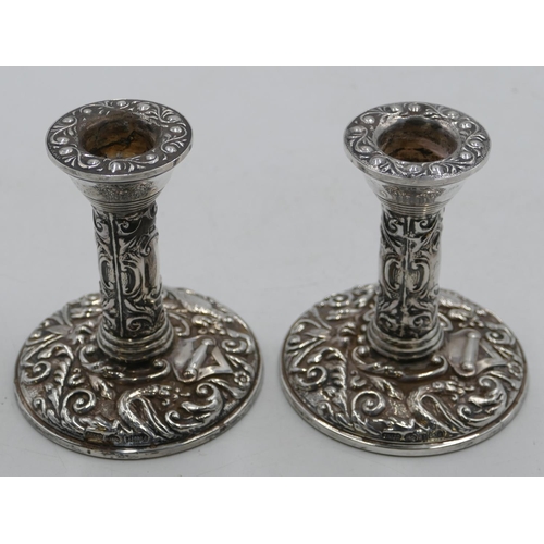 266 - A pair of Birmingham silver dwarf candlesticks with allover embossed bird, floral and scroll decorat... 