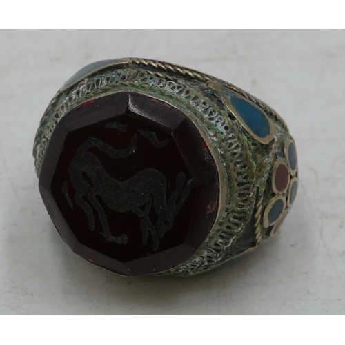 303 - Large Eastern style ring set with octagonal red stone with allover part enamelled decoration. Size X