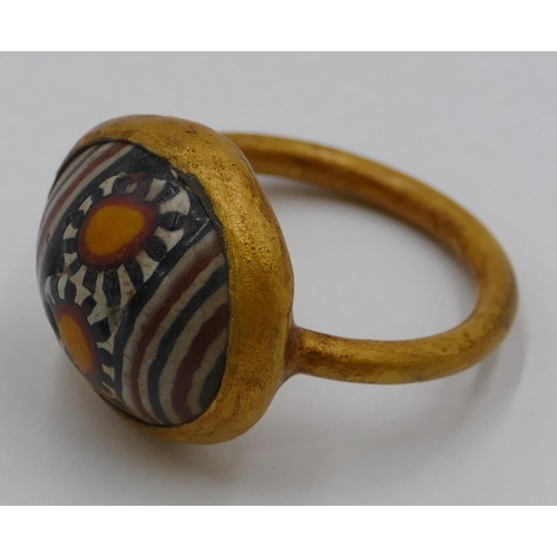 306 - A gilt ring with circular painted decoration. Size U/V