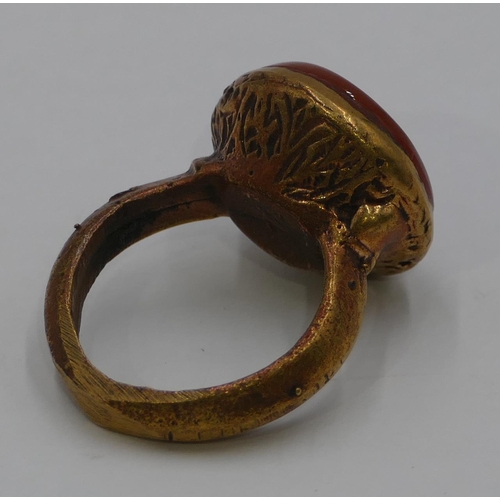 308 - A Roman style gilt ring set with a circular red stone engraved with a figurehead. Size Q