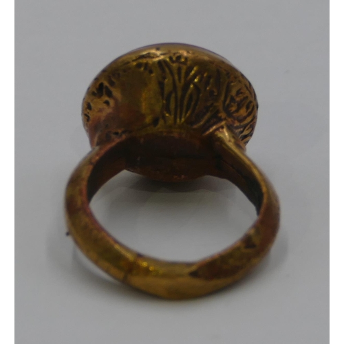 308 - A Roman style gilt ring set with a circular red stone engraved with a figurehead. Size Q