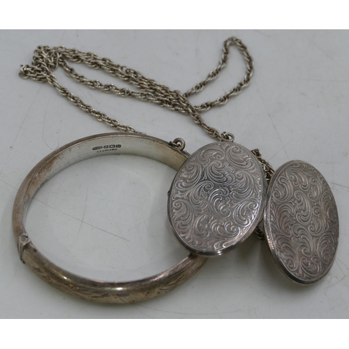 314 - An oval silver locket with chased decoration, with chain, a Birmingham silver hinged bangle, 51.7 gr... 