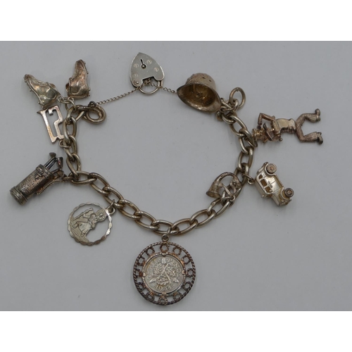 321 - A silver linked bracelet with padlock clasp, mounted with 9 charms, 53.7 grams.