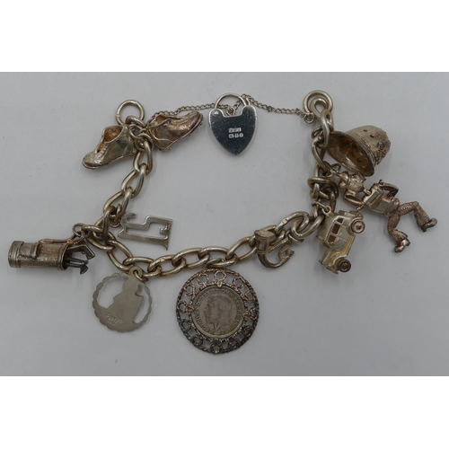 321 - A silver linked bracelet with padlock clasp, mounted with 9 charms, 53.7 grams.