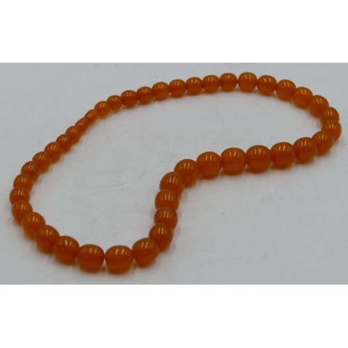 394 - An amber style graduated bead necklace, 65cm long.