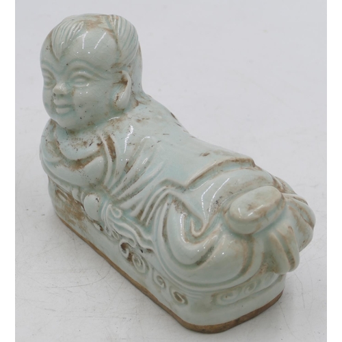 50 - An Oriental china pillow in the form of a reclining child on pale green ground,21cm long.