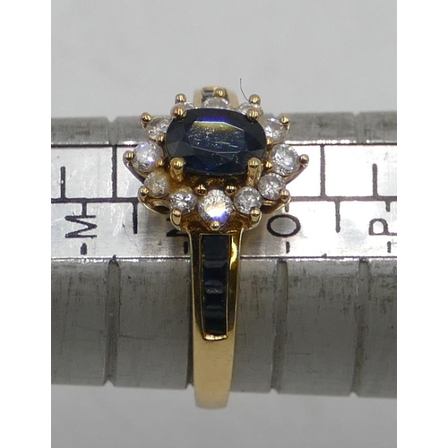 514 - An 18ct gold ladies' oval cluster ring set with centre sapphire and surrounded by 12 small diamonds ... 