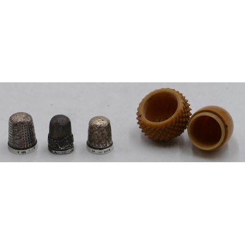 574 - 3 silver thimbles and a Treen thimble case in form of an acorn. (4)