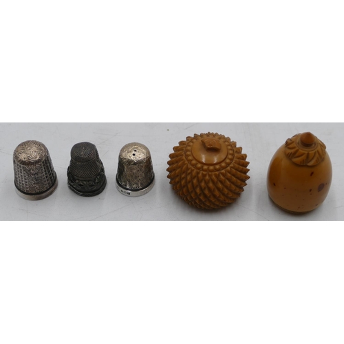 574 - 3 silver thimbles and a Treen thimble case in form of an acorn. (4)