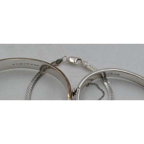 576 - A silver hinged bangle, another silver hinged bangle and a silver bracelet. (3)