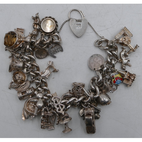 578 - A heavy silver linked bracelet mounted with 35 mostly silver charms, 168.5 grams gross.