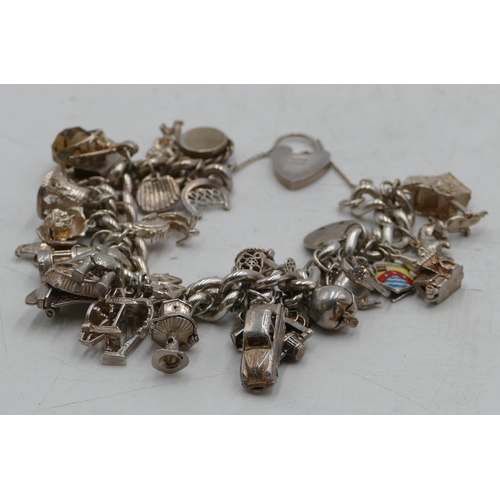 578 - A heavy silver linked bracelet mounted with 35 mostly silver charms, 168.5 grams gross.