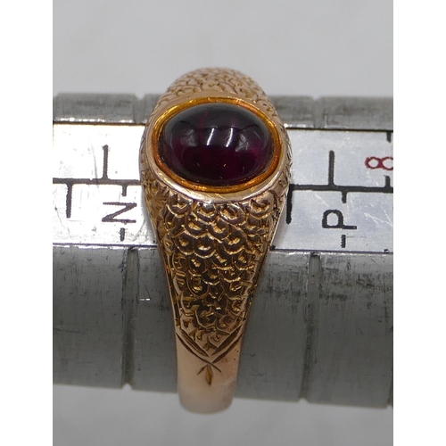 584 - A 9ct gold ring set with cabochon red stone with chased decoration, size O, 3.4 grams.