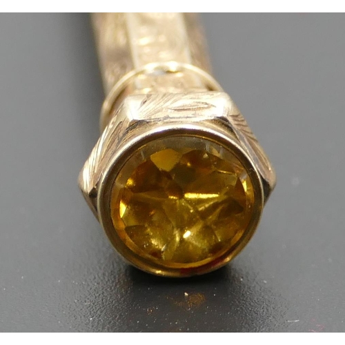 597 - A gold coloured hexagonal propelling pencil mounted with citrine and allover engraved decoration, 9.... 