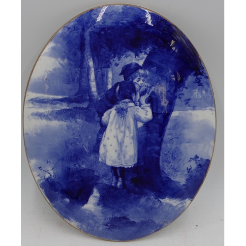 70 - A Doulton Burslem  oval hanging plaque on blue and white ground depicting 2 children hiding behind a... 