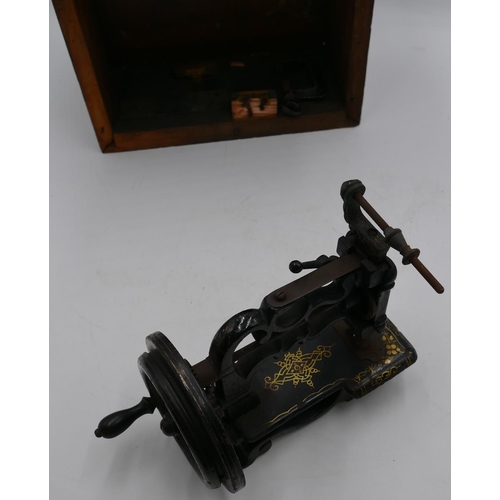 724 - A small early sewing machine (base missing), 20cm high, boxed.