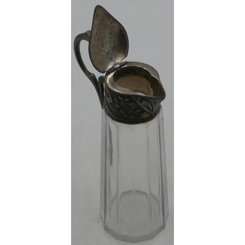 733 - An Arts & Crafts cut glass water jug with pewter neck, scroll handle and hinged lid with embossed fl... 