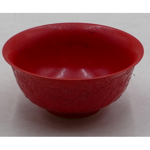 74 - An Oriental red round trumpet shaped bowl with raised dragon decoration, 15.8cm diameter.