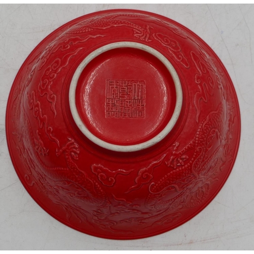 74 - An Oriental red round trumpet shaped bowl with raised dragon decoration, 15.8cm diameter.