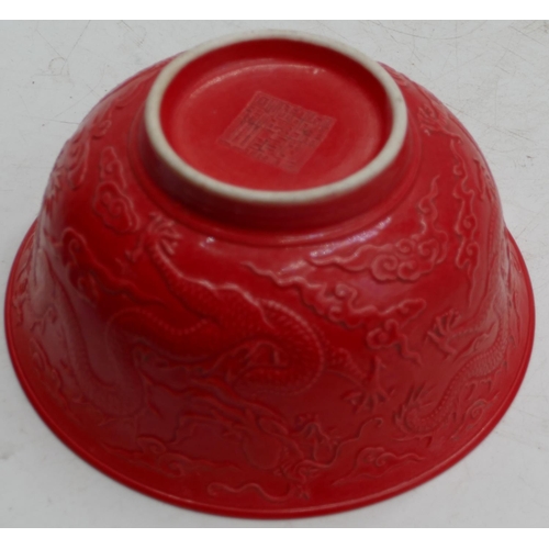 74 - An Oriental red round trumpet shaped bowl with raised dragon decoration, 15.8cm diameter.