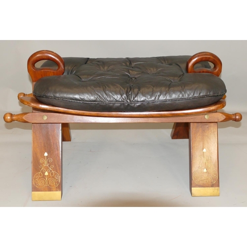 871 - An Eatsern hard wood camel stool with inlaid brass decoration, black leather studded seat, 77cm long... 