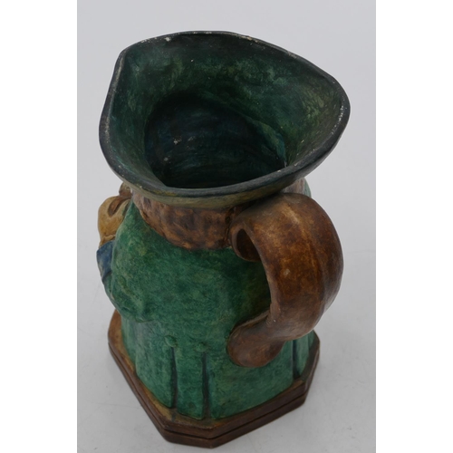 89 - A Compton pottery Toby jug in form of a seated gentleman wearing a green coat holding a jug, 18.7cm ... 