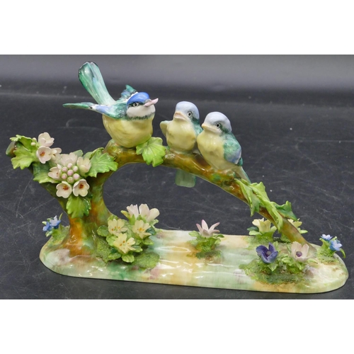 114 - A Crown Staffordshire group of 3 perched birds modelled by JT Jones with all over encrusted floral d... 