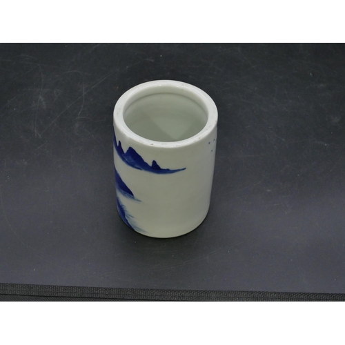 122 - An Oriental cylindrical blue and white brush pot with landscape decoration, 11cm high.