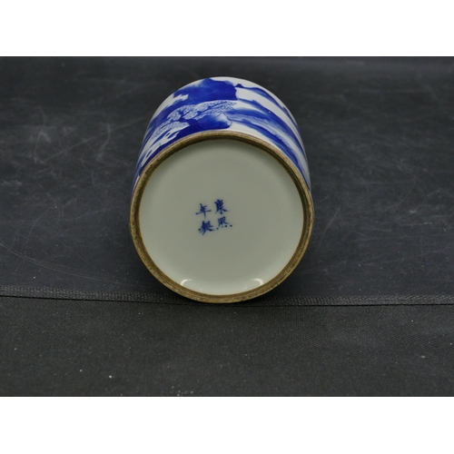 122 - An Oriental cylindrical blue and white brush pot with landscape decoration, 11cm high.