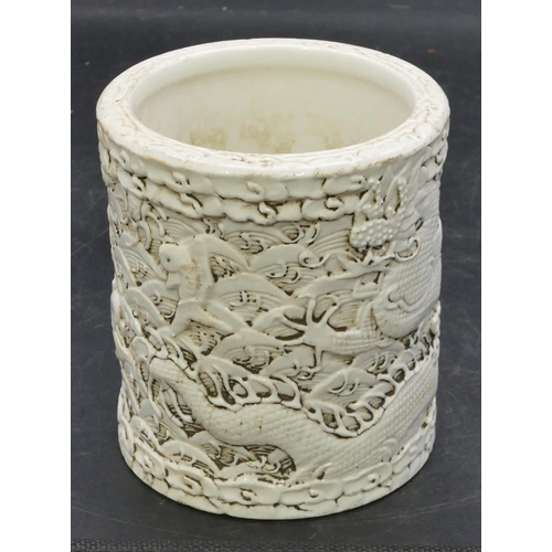 174 - An Oriental cylindrical brush pot on white ground with raised dragon and fish decoration, 11.6cm hig... 