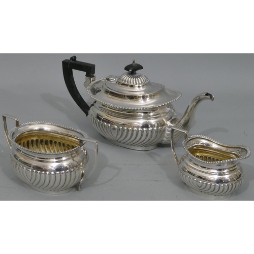 275 - A silver plated 3-piece tea service with half embossed reeded decoration, comprising teapot with ebo... 